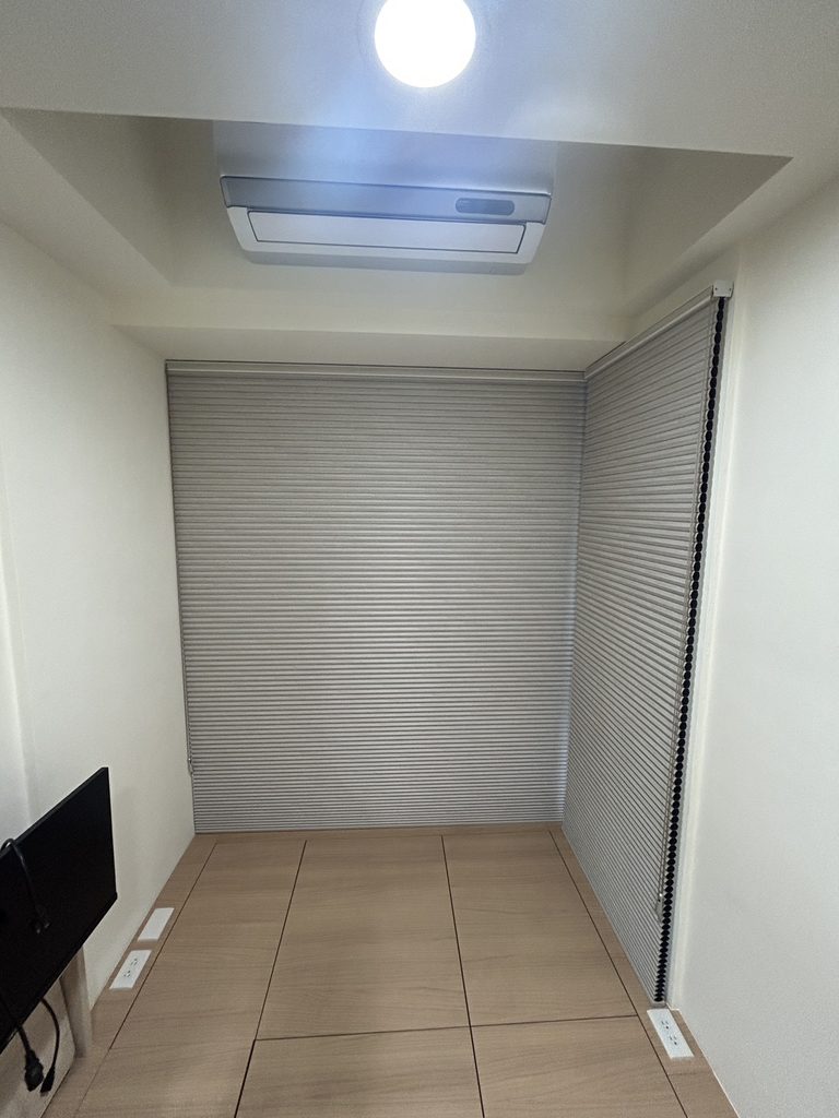 新北市土城區|光影與私密的彈性設計,客廳、主臥、客書房的布簾、風琴簾與電動捲簾全域規劃 8 現代極簡風琴簾布置: 暖灰色風琴簾與淺木紋地板交織出溫暖明亮的視覺感,極簡的幾何折線為空間注入現代簡約的設計語彙。