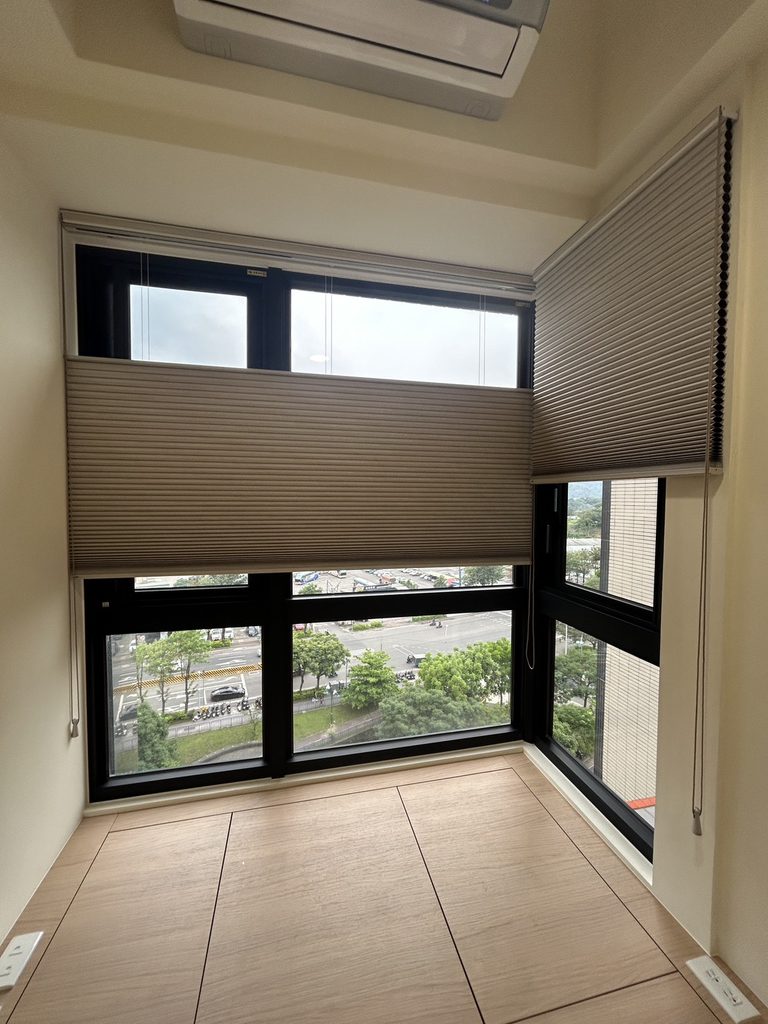 新北市土城區|光影與私密的彈性設計,客廳、主臥、客書房的布簾、風琴簾與電動捲簾全域規劃 7 精準客製的蜂巢紋理:正面特寫轉角風琴簾,清晰展現奶茶色布料的橫向折痕與六角蜂巢結構。風琴簾精準填滿窗框,與牆面、冷氣、地板收邊乾淨,展現高品質的量身打造感。